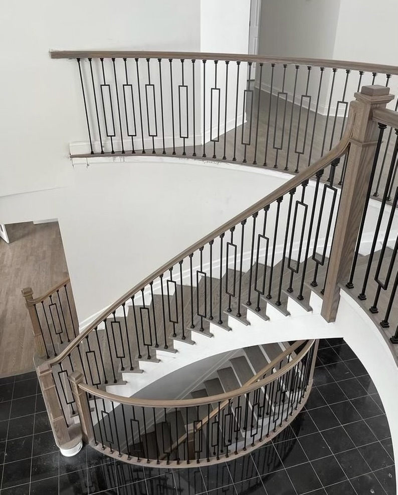 Hudson project photo of a curved staircase with wood handrails and black metal balusters